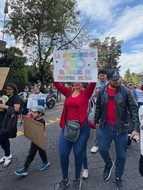 Familia marchando junto a sus hijos con un cartel que dice 'La diversidad es el color de nuestra familia'