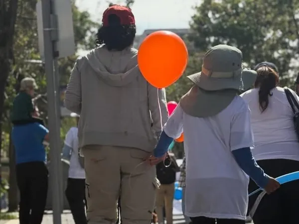 Padre e hijo caminando de la mano en una marcha de concienciación sobre el autismo